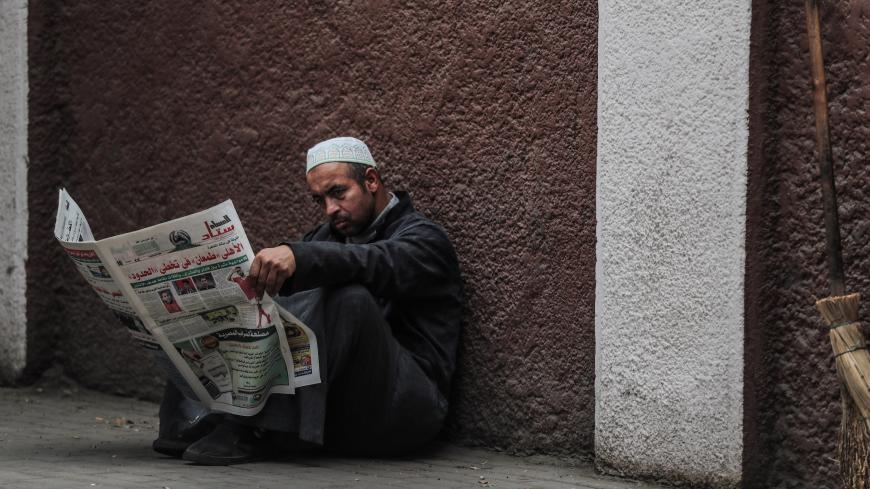 A man reads a newspaper on a sidewalk in the Zamalek district of western Cairo on December 15, 2019. (Photo by Mohamed el-Shahed / AFP) (Photo by MOHAMED EL-SHAHED/AFP via Getty Images)