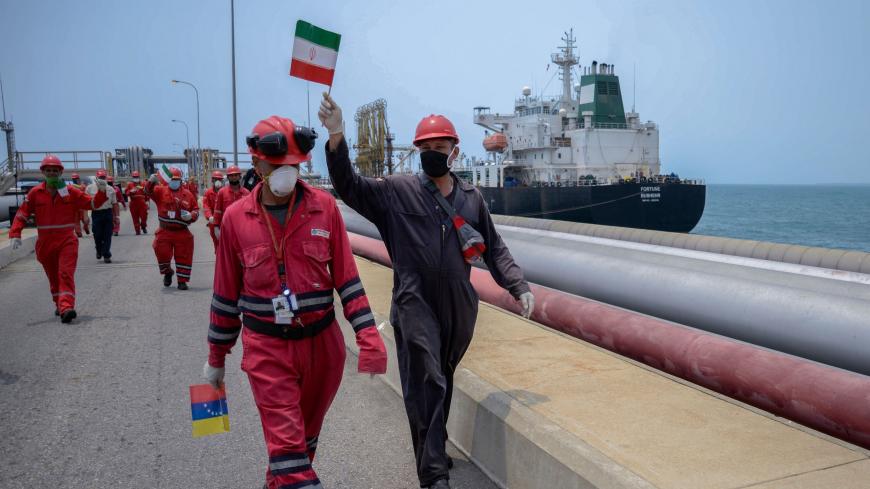 TOPSHOT - A worker of the Venezuelan state oil company PDVSA waves an Iranian flag as the Iranian-flagged oil tanker Fortune docks at the El Palito refinery in Puerto Cabello, in the northern state of Carabobo, Venezuela, on May 25, 2020. - The first of five Iranian tankers carrying much-needed gasoline and oil derivatives docked in Venezuela on Monday, Caracas announced amid concern in Washington over the burgeoning relationship between countries it sees as international pariahs. (Photo by - / AFP) (Photo 