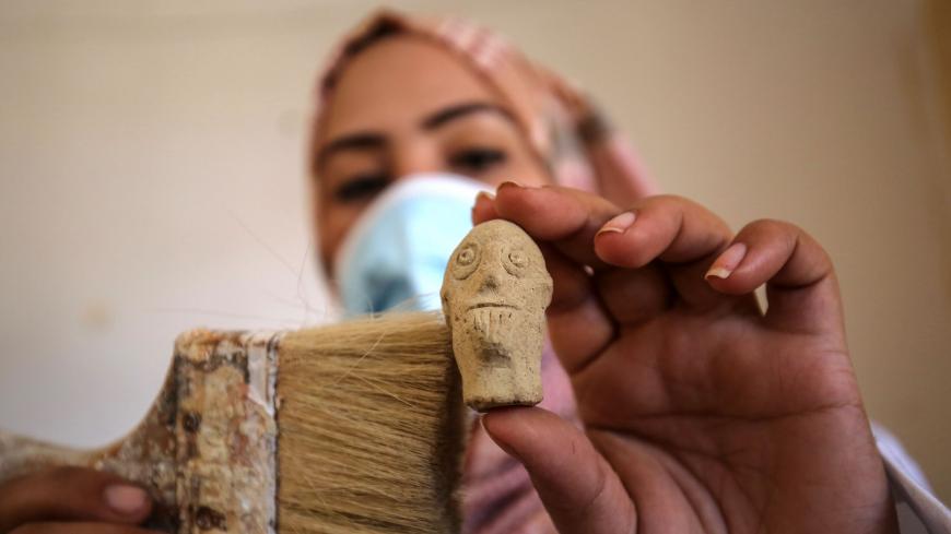 A Palestinian woman wearing a face mask amid the Covid-19 pandemic cleans artifacts at her family-run al-Qarara Cultural Museum, as visitors stopped coming following Gaza authoritiess decision to close tourist places to prevent the spread of the coronavirus, in the southern Gaza Strip on October 19, 2020. (Photo by SAID KHATIB / AFP) (Photo by SAID KHATIB/AFP via Getty Images)
