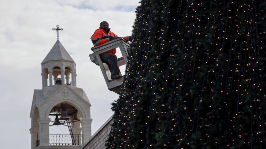 A worker sets up lights on a giant Christmas tree at the Church of the Nativity compound as mass was celebrated to ceremonially launch the beginning of the Christmas season, in Bethlehem in the Israeli-occupied West Bank November 28, 2020. (Photo by Emmanuel DUNAND / AFP) (Photo by EMMANUEL DUNAND/AFP via Getty Images)