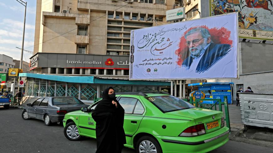 A woman walk by a billboard in honour of slain nuclear scientist Mohsen Fakhrizadeh in the Iranian capital Tehran, on November 30, 2020. - Iran laid to rest a nuclear scientist in a funeral befitting a top "martyr", vowing to redouble his work after an assassination pinned on arch-foe Israel. Fakhrizadeh died on November 27 from his wounds after assailants targeted his car and engaged in a gunfight with his bodyguards outside the capital, according to the defence ministry, heightening tensions once more bet
