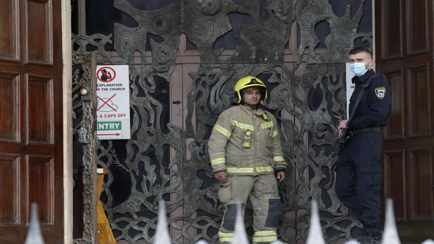 Israeli police and firefighters stand at the entrance of the Church of All Nations in the Garden of Gethsemane in east Jerusalem after an arson attempt, on December 4, 2020. - Israeli police said in a statement they were questioning a 49-year-old suspect who had "poured flammable liquid inside the church", causing damage. (Photo by Ahmad GHARABLI / AFP) (Photo by AHMAD GHARABLI/AFP via Getty Images)