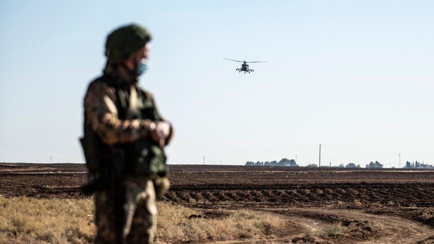A Russian Mil Mi-17 military helicopter flies by a soldier during a joint Russian-Turkish patrol convoy in the eastern countryside of the town of Darbasiyah near the border with Turkey in Syria's northeastern Hasakah province on December 7, 2020. (Photo by Delil SOULEIMAN / AFP) (Photo by DELIL SOULEIMAN/AFP via Getty Images)