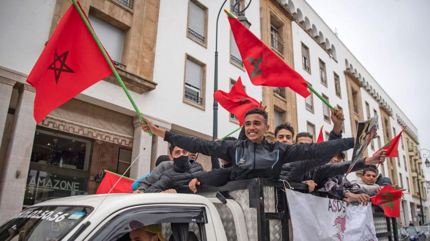 Moroccans celebrate in front of the parliament building in Rabat on December 13, 2020, after the US adopted a new official map of Morocco that includes the disputed territory of Western Sahara. - Western Sahara is a disputed and divided former Spanish colony, mostly under Morocco's control, where tensions with the pro-independence Polisario Front have simmered since the 1970s. Morocco became the fourth Arab state this year, after the United Arab Emirates, Bahrain and Sudan, to announce it had agreed to norm