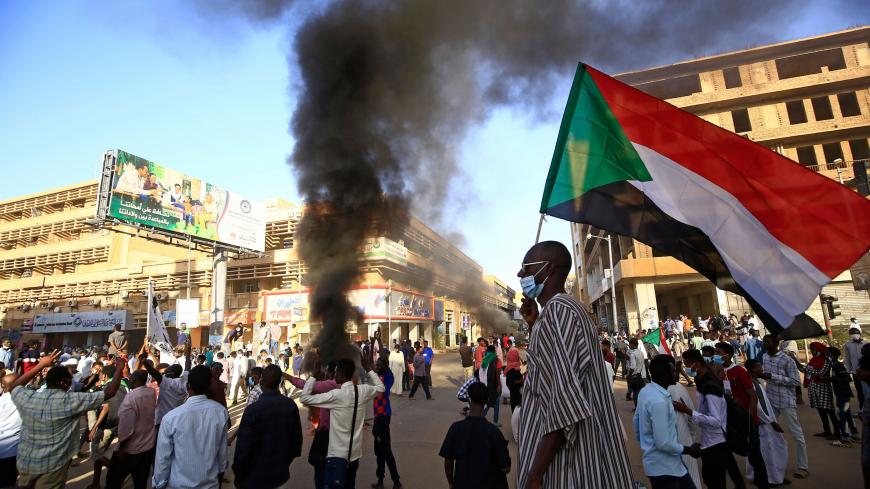 A Sudanese man wearing a face mask waves his country's national flag during protests in the capital Khartoum to mark the second anniversary of the start of a revolt that toppled the previous government, on December 19, 2020. - Frustrated by the lack of change in their daily lives, thousands of demonstrators, mostly young, marched in several towns in Sudan. (Photo by ASHRAF SHAZLY / AFP) (Photo by ASHRAF SHAZLY/AFP via Getty Images)