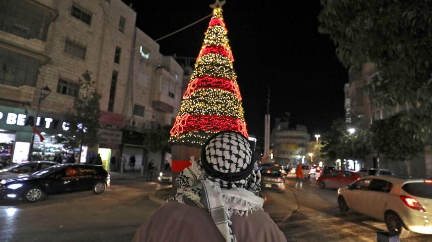 A Palestinian man looks at a Christmas tree in the West Bank city of Ramallah on December 21, 2020 during strict COVID-19 restrictions imposed by the Palestinian authorities to curb the spread of the novel coronavirus. (Photo by ABBAS MOMANI / AFP) (Photo by ABBAS MOMANI/AFP via Getty Images)
