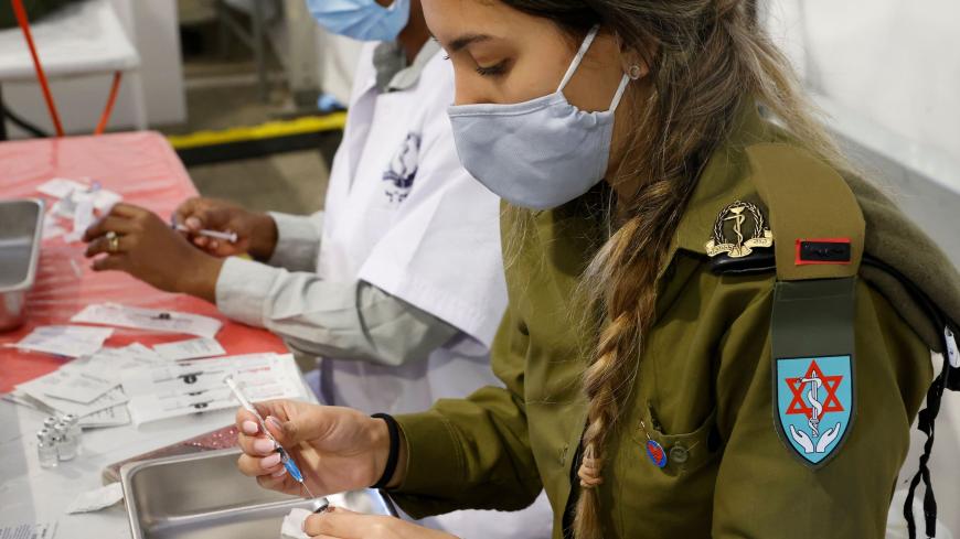 An Israeli military medic prepares to administer the Pfizer-BioNTech COVID-19 vaccine at the medical centre of Tzrifin military base in the Israeli town of Rishon Lezion on December 28, 2020. (Photo by JACK GUEZ / AFP) (Photo by JACK GUEZ/AFP via Getty Images)