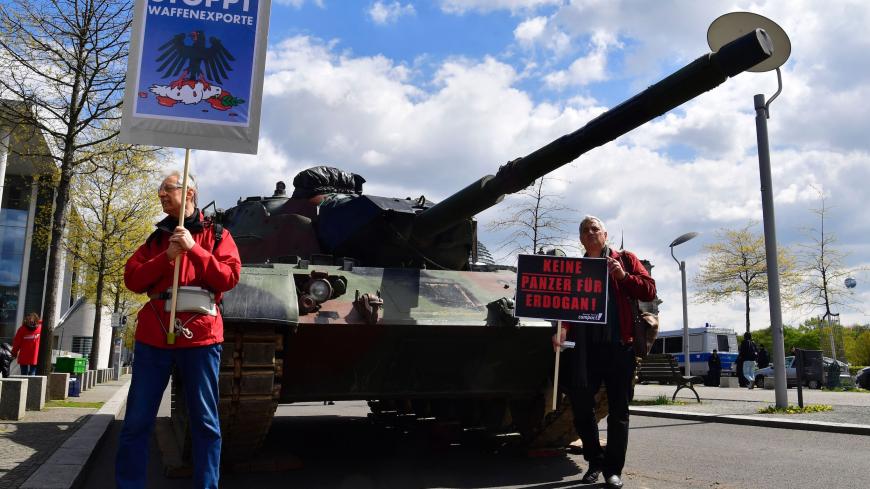 Activists stand in front of a tank and hold up signs reading "stop exports of weapons" to protest against plans of German military technology group Rheinmetall to built a tank factory in Turkey, on April 26, 2017 in front of the Bundestag in Berlin. / AFP PHOTO / John MACDOUGALL        (Photo credit should read JOHN MACDOUGALL/AFP via Getty Images)