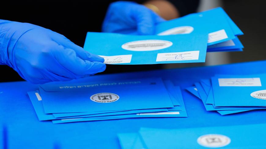 An electoral worker counts ballots cast by Israelis under home quarantine after returning from Coronavirus infected zones,  in the central Israeli town of Shoham on March 4, 2020 - Some 4,200 ballots from 17 polling stations set up for people under quarantine were gathered and counted by workers wearing protective gear under a tent at the Central Elections Commissions logistical centre in Shoham to be counted. (Photo by Emmanuel DUNAND / AFP) (Photo by EMMANUEL DUNAND/AFP via Getty Images)