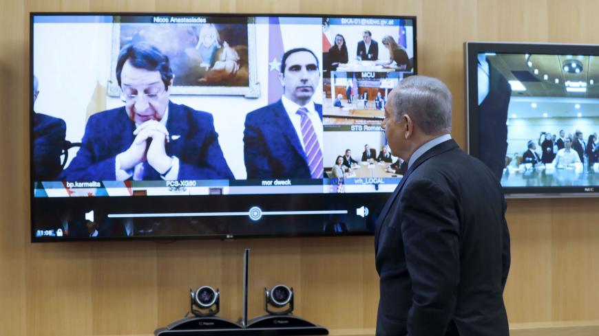 Israeli Prime Minister Benjamin Netayahu stands in front of a screen showing the president of Cyprus, Nicos Anastasiades, during a video conference with European leaders in order to discuss challenges and cooperation between various countries in dealing with COVID-19 coronavirus, at the Foreign Ministry in Jerusalem on March 9, 2020. (Photo by MENAHEM KAHANA / AFP) (Photo by MENAHEM KAHANA/AFP via Getty Images)