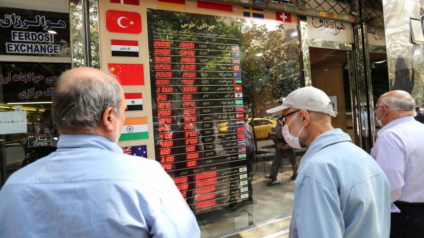 Iranians check a display board at a currency exchange shop in the capital Tehran, on September 29, 2020. - For Iran, struggling from sanctions imposed under Washington's policy of "maximum pressure", the US presidential race raises hope of change -- but also fears that life could get even worse. (Photo by ATTA KENARE / AFP) (Photo by ATTA KENARE/AFP via Getty Images)