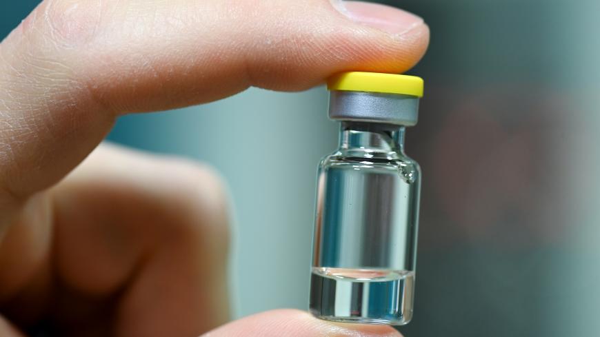 DESSAU, GERMANY - NOVEMBER 23: An employee holds an ampoule into which the vaccine is later filled as German Health Minister Jens Spahn tours the lab facilities of vaccine maker IDT Biologika during the second wave of the coronavirus pandemic on November 23, 2020 in Dessau, Germany. IDT Biologika is currently conducting human trials for its potential vaccine against Covid-19. During the company visit, Spahn announced the planned purchase at least five million vaccine doses.  (Photo by Hendrik Schmidt-Pool/G