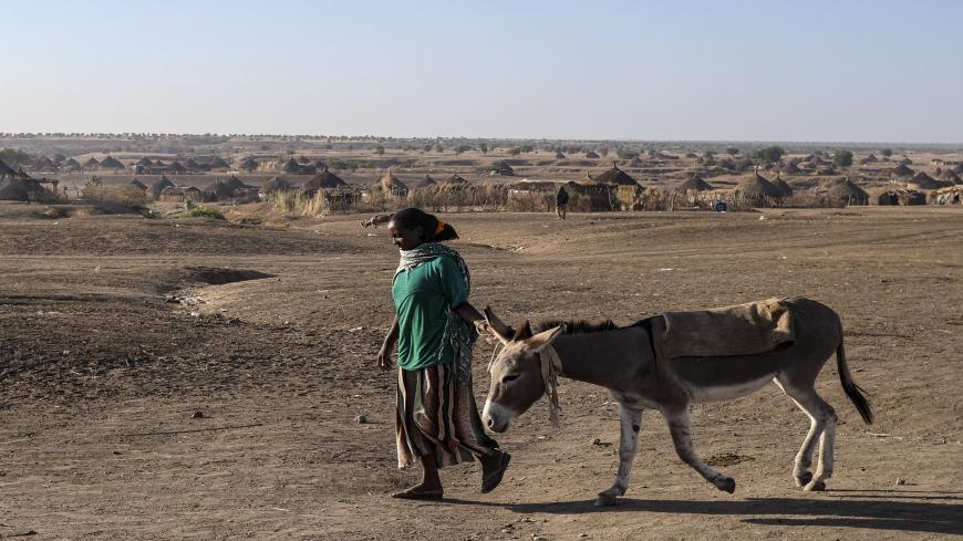 HAMDAYET, SUDAN - DECEMBER 6: A woman walks with a donkey as refugees from the Tigray region of Ethiopia wait to be transferred to a camp with more infrastructure at a UNHCR reception area in the east Sudanese border village of Hamdayet on December 6, 2020 in Hamdayet, Sudan. Last week, the Ethiopian government declared victory in its nearly month-long battle with the Tigray People's Liberation Front (TPLF), which sent 45,000 people fleeing to Sudan and displaced thousands more within the Tigray Region. In 