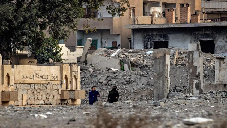 Women walk between destroyed buildings in the northern Syrian city of Raqa, the former Syrian capital of the Islamic State (IS) group, on December 20, 2020. - The Kurdish-led Syrian Democratic Forces overran Raqa in 2017, after years of what residents described as IS's brutal rule, which included public beheading and crucifixions. (Photo by Delil SOULEIMAN / AFP) (Photo by DELIL SOULEIMAN/AFP via Getty Images)