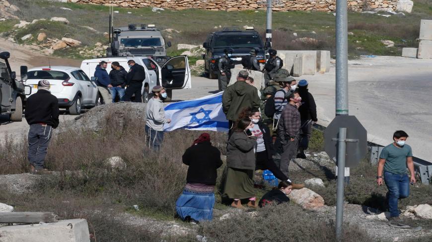 Israeli settlers gather at a junction with security forces arriving to block Palestinians trying to reach their lands confiscated by Israeli authorities, during a protest in the village of Halhul, north of Hebron in the occupied West Bank, on January 4, 2021. (Photo by HAZEM BADER / AFP) (Photo by HAZEM BADER/AFP via Getty Images)