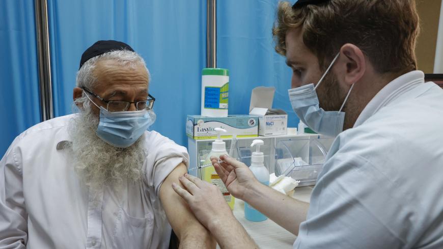A healthcare worker administers a COVID-19 vaccine at Clalit Health Services, in the ultra-Orthodox Israeli city of Bnei Brak, on January 6, 2021. (Photo by JACK GUEZ / AFP) (Photo by JACK GUEZ/AFP via Getty Images)