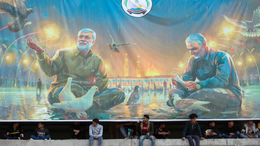 Iraqi youths watch an event celebrating the inauguration of a street named after the late Iraqi commander Abu Mahdi al-Muhandis in the southern city of Basra on January 8, 2021, more than a year after a US drone strike killed Iran's revered commander Qasem Soleimani and his Iraqi lieutenant Muhandis (image) near the capital. (Photo by Hussein FALEH / AFP) (Photo by HUSSEIN FALEH/AFP via Getty Images)