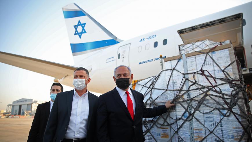 Israel's Prime Minister Benjamin Netanyahu (R) and Health Minister Yuli Edelstein (C) attend a ceremony for the arrival of a plane carrying a shipment of Pfizer-BioNTech anti-coronavirus vaccine, at Ben Gurion airport near the Israeli city of Tel Aviv on January 10, 2021. - Netanyahu announced earlier this week that he had signed a deal for enough doses of the Pfizer-BioNTech vaccine for all Israelis over 16 to be innoculated. Israel, with a population of nine million, has recorded over 3,600 deaths from th