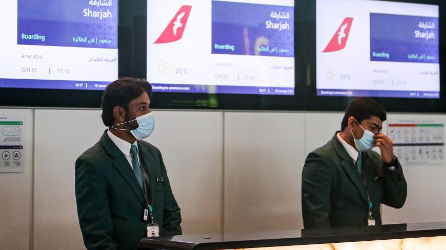 Mask-clad employees of Air Arabia wait to assist passengers board the first flight to Sharjah after the resumption of air travel between Qatar and the United Arab Emirates, at Qatar's Hamad International Airport on January 18, 2021. - The first direct flights since 2017 between Qatar and its former rivals Egypt and the UAE took to the skies on January 18, following the end of a regional crisis. The first commercial flight from Qatar to Egypt in three and a half years, an EgyptAir service to Cairo, took off 