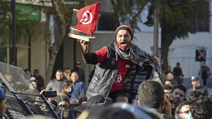 A Tunisian protester lifts a flag-clad birdcage during an anti-government demonstration on the Habib Bourguiba avenue in the capital Tunis, on January 19, 2021. - Tunisia braced for further protests after hundreds were arrested in four nights of street clashes between riot police and disaffected youths in cities across the North African country. (Photo by FETHI BELAID / AFP) (Photo by FETHI BELAID/AFP via Getty Images)