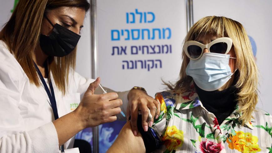 An Israeli health worker administers a dose of the Pfizer-BioNtech Covid-19 vaccine, at the Clalit Health Services installed at the Pais Arena Sport Hall in Jerusalem, on January 21, 2021. (Photo by Emmanuel DUNAND / AFP) (Photo by EMMANUEL DUNAND/AFP via Getty Images)