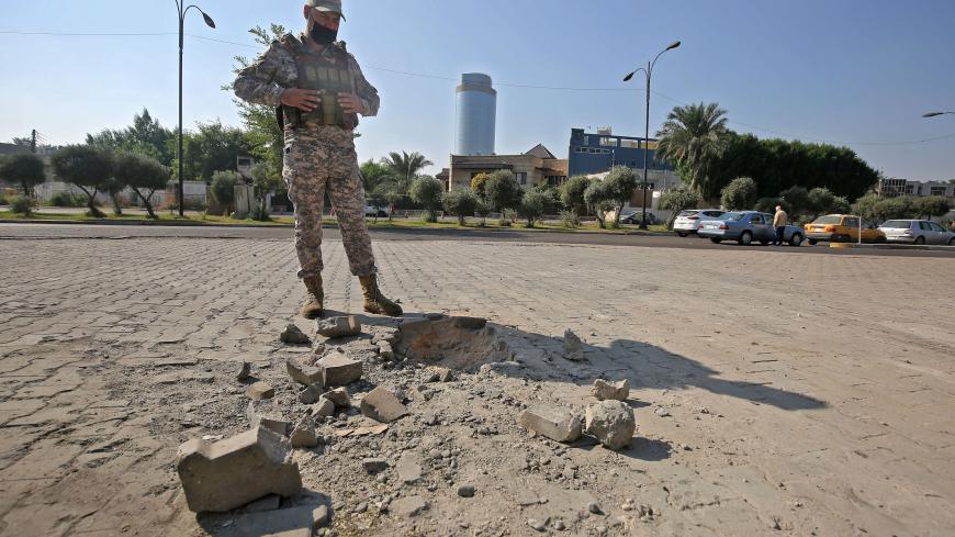 A member of the Iraqi security forces inspects the damage outside the Zawraa park in the capital Baghdad on November 18, 2020, after volley of rockets slammed into the Iraqi capital breaking a month-long truce on attacks against the US embassy. - According to the Iraqi military, four of the rockets landed in the high-security Green Zone, where the US embassy and other foreign missions are based.  Another three rockets also hit other parts of Baghdad, killing one girl and wounding five civilians. All seven r