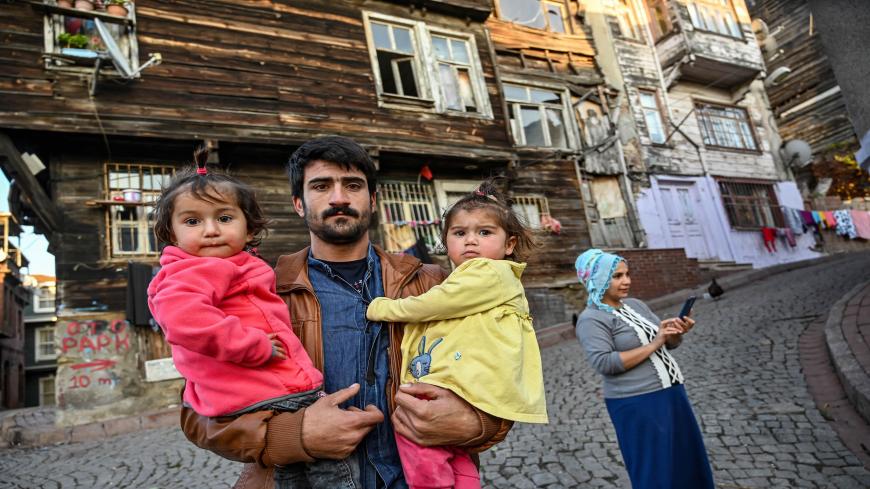 A man holds his children near their home in a deserted street near the Suleymaniye mosque in Istanbul during a week-end curfew aimed at curbing the spread of the Covid-19 pandemic caused by the novel coronavirus on December 6, 2020. - Under the new restrictions beginning from December 1, a curfew will be imposed on weekdays from 9:00 pm. to 5:00 am. Over the weekend the lockdown will last from 9:00 pm Friday until 5:00 am on Monday. (Photo by Ozan KOSE / AFP) (Photo by OZAN KOSE/AFP via Getty Images)
