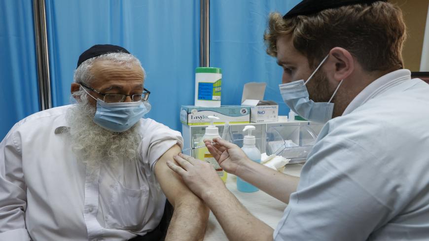 A healthcare worker administers a COVID-19 vaccine at Clalit Health Services, in the ultra-Orthodox Israeli city of Bnei Brak, on January 6, 2021. (Photo by JACK GUEZ / AFP) (Photo by JACK GUEZ/AFP via Getty Images)
