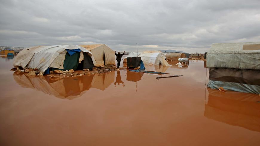 A Syrian man reacts as water floods tents at a camp for the internally displaced near the town of Kafr Lusin in the rebel-held northwestern province of Idlib, by the border with Turkey, on January 19, 2021. - Flooding following heavy rain at displacement camps in northwest Syria has killed a child and damaged or destroyed the tents of thousands of people, according to residents and aid workers. (Photo by Aaref WATAD / AFP) (Photo by AAREF WATAD/AFP via Getty Images)