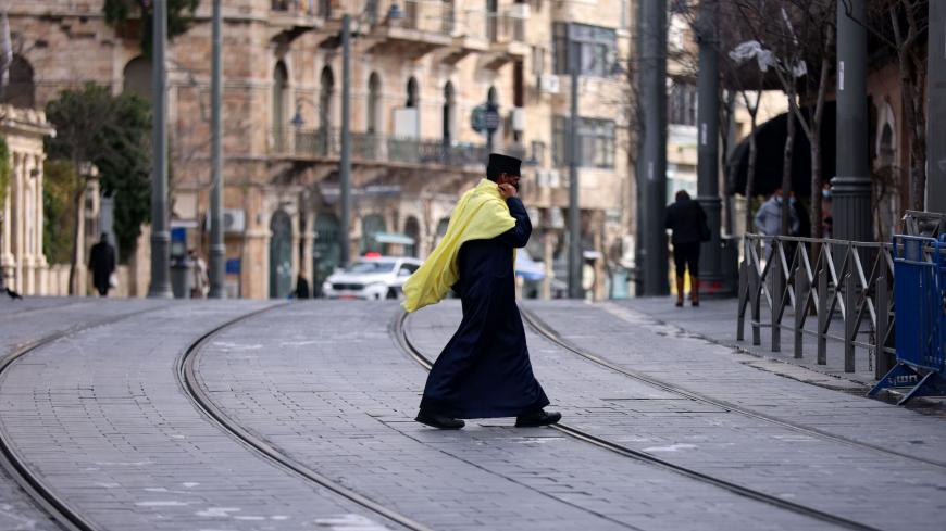 TOPSHOT - A priest crosses a nearly deserted street during a lockdown imposed by the authorities in a bid to fight spread of the coronavirus in the centre of Jerusalem, on January 28, 2021. (Photo by Emmanuel DUNAND / AFP) (Photo by EMMANUEL DUNAND/AFP via Getty Images)