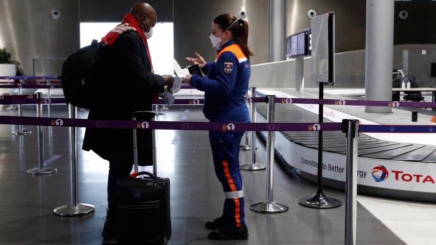 A member of the French Civil Defence checks an air traveller's documents at Paris-Charles de Gaulle airport in Roissy, north of Paris, on February 5, 2021, after France implemented tough border restrictions as part of new efforts to contain Covid-19 (novel coronavirus) infections. - France on February 1, 2021, curbed international travel by banning most flights outside the European Union. Only urgent reasons for travel are accepted and border police require written proof before allowing passengers to board.