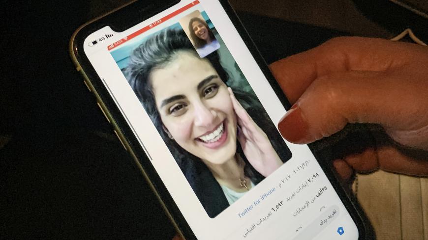 This picture taken February 10, 2021 in Saudi Arabia's capital Riyadh shows a woman viewing a tweet posted by the sister of Saudi activist Loujain al-Hathloul, Lina, showing a screenshot of them having a video call following Hathloul's release after nearly three years in detention. - Saudi authorities on February 10 released the prominent women's rights activist, her family said, as the kingdom comes under renewed US pressure over its human rights record. Hathloul, 31, was arrested in May 2018 with about a 