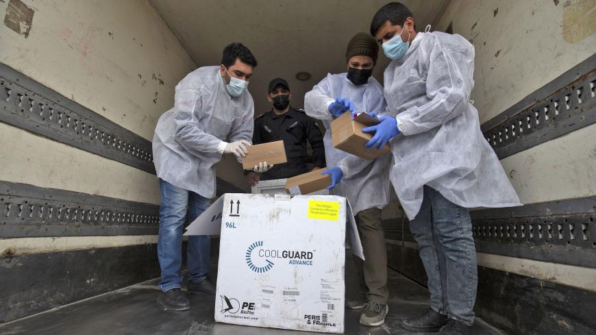 Palestinian health workers unload the first arriving shipment of doses of Russia's Sputnik V vaccine for COVID-19 coronavirus disease, on the Palestinian side of the Kerem Shalom border crossing south of Rafah in the southern Gaza Strip on February 17, 2021. - An initial batch of coronavirus vaccines, enough to fully innoculate 1,000 people, arrived in Gaza after Israel had blocked the shipment earlier in the week. The Israeli military department responsible for civilian affairs in the occupied Palestinian 