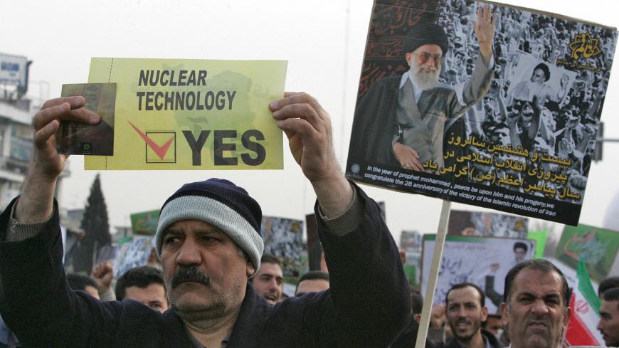 Tehran, IRAN: An Iranian man carries a placard in support of nuclear technology as another waves a portrait of Iran's supreme leader Ayatollah Ali Khamenei during a rally to mark the 28th anniversary of the Islamic revolution in Tehran 11 February 2007. Tens of thousands of Iranians took to the streets of Tehran today in an annual show of support for the Islamic revolution and to back the country's controversial nuclear programme. Throngs of people were crowding into Tehran's massive Azadi square, where Ira