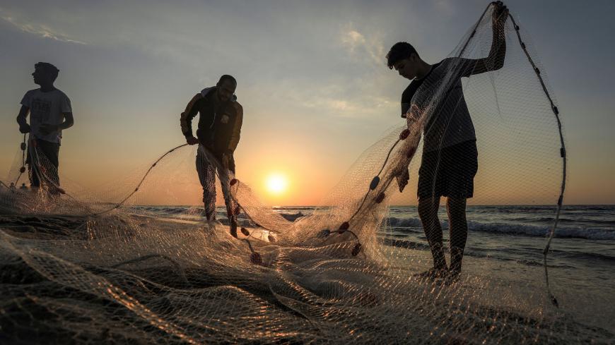 Palestinian fishermen gather their net along a beach in Gaza City at sunset on December 2, 2020. (Photo by MAHMUD HAMS / AFP) (Photo by MAHMUD HAMS/AFP via Getty Images)