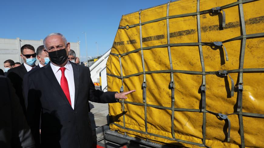 Israeli Prime Minister Benjamin Netanyahu gestures during a ceremony to mark the arrival of a plane of the international courier company DHL, carrying over 100,000 of doses of the first batch of Pfizer vaccines which landed at Ben Gurion Airport near Tel Aviv, on December 9, 2020. - According to media reports, the launch of a national COVID-19 immunisation campaign is set to begin on December 20. (Photo by Abir SULTAN / POOL / AFP) (Photo by ABIR SULTAN/POOL/AFP via Getty Images)
