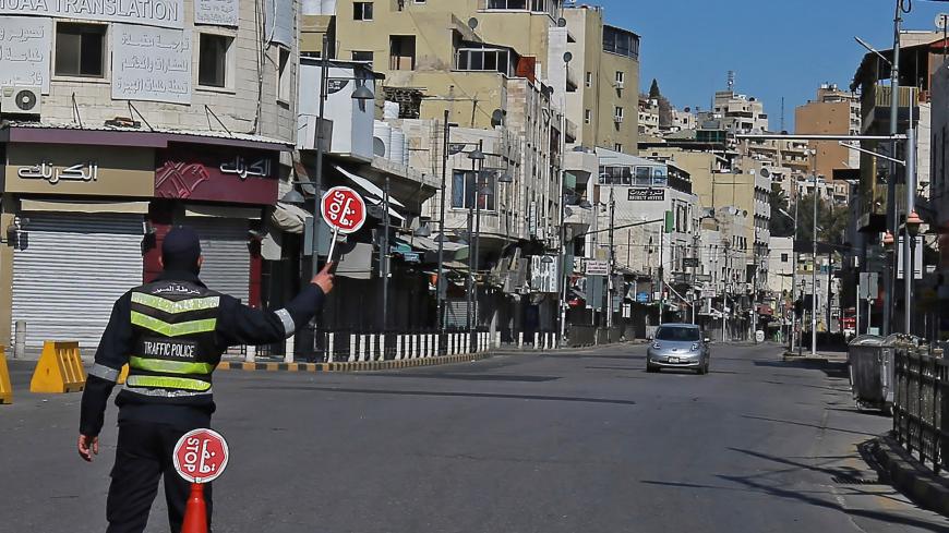 A policeman holds a stop sign in an almost deserted avenue in the Jordanian capital Amman, during a lockdown due to the coronavirus panemic, on February 26, 2021. (Photo by Khalil MAZRAAWI / AFP) (Photo by KHALIL MAZRAAWI/AFP via Getty Images)