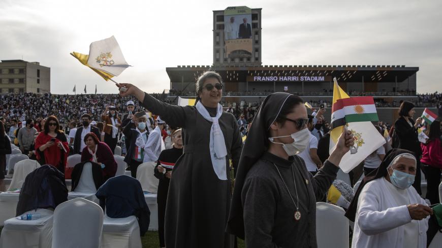 ERBIL, IRAQ - MARCH 07: A nun waves a flag as Pope Francis arrives to conduct a mass at the Franso Hariri Stadium on March 07, 2021 in Erbil, Iraq. PPope Francis arrived in Erbil, the final stop of his historic four-day visit, the first-ever papal visit to Iraq. In his first foreign trip since the start of the pandemic, Pope Francis visited Baghdad, Najaf, Erbil, and the cities of Qaraqosh and Mosul, which were heavily destroyed by ISIS. Although the trip is seen as an act of solidarity, the Vatican has bee