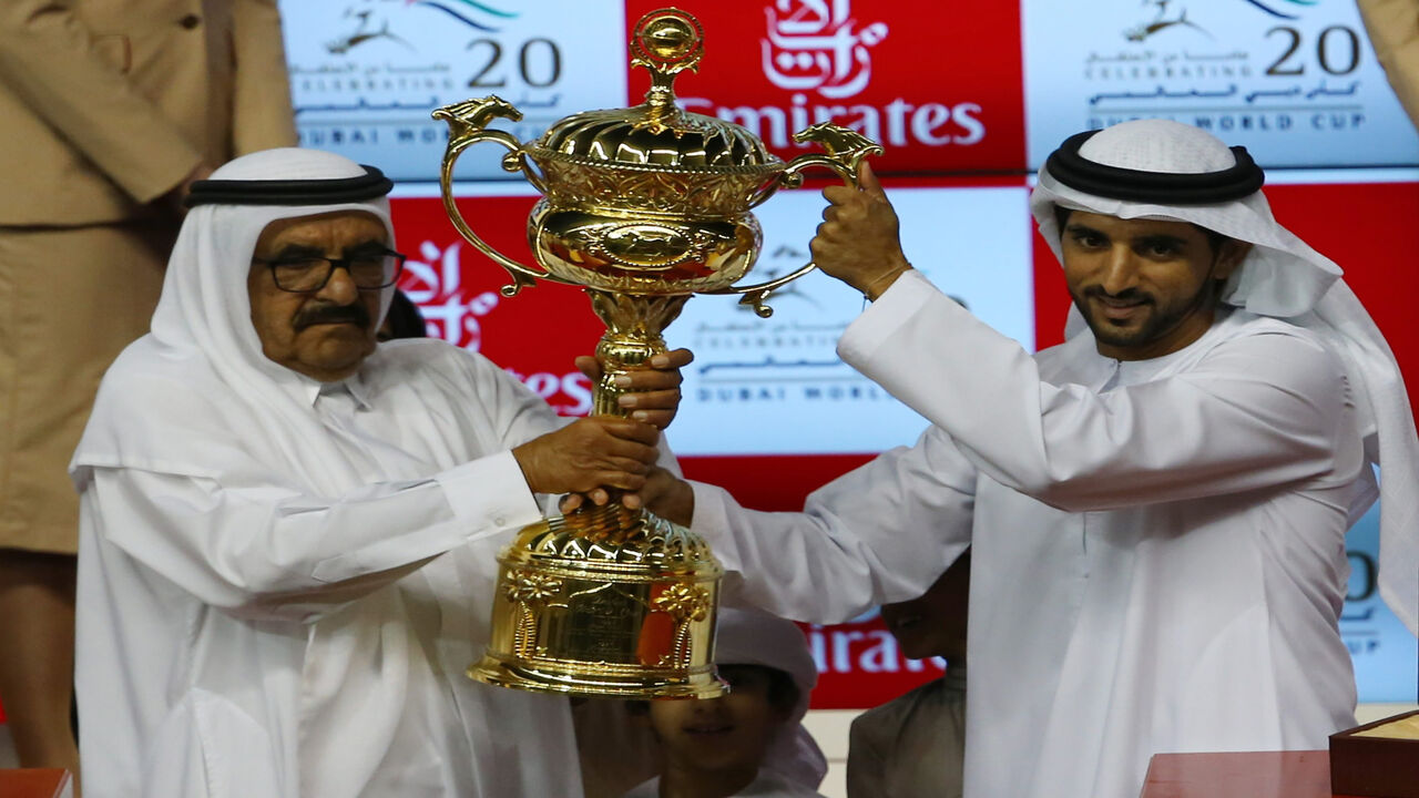 Crown Prince of Dubai Sheikh Rashid bin Mohammed bin Rashid Al Maktoum (R) receives the trophy from his uncle and United Arab Emirates' Finance Minister Sheikh Hamdan bin Rashid Al Maktoum, after his horse Prince Bishop won the $10 million Dubai World Race, Meydan racecourse in Dubai, March 28, 2015.