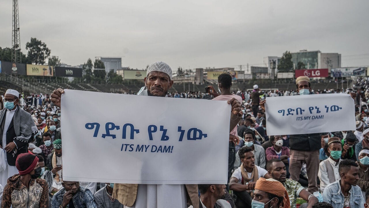 People hold placards to express their support for Ethiopia's mega-dam on the Blue Nile River as faithfuls gather to attend the Eid al-Fitr morning prayer sermon at a soccer stadium in Addis Ababa, Ethiopia, on May 13, 2021 as Muslims across the globe mark the end of the Holy month of Ramadan. 