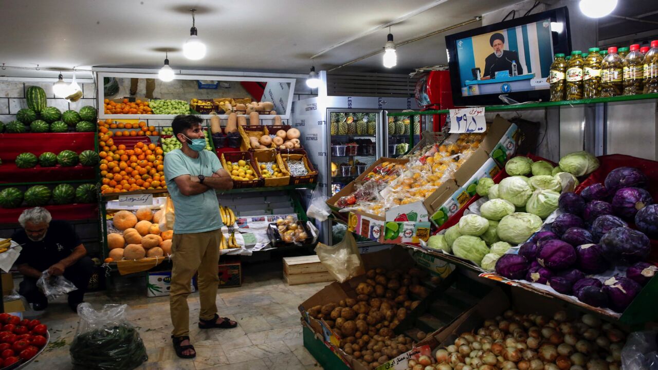 An Iranian man watches candidate Ebrahim Raisi speaking during the first televised debate between presidential candidates, at a fresh produce shop in the capital, Tehran, on June 5, 2021. 