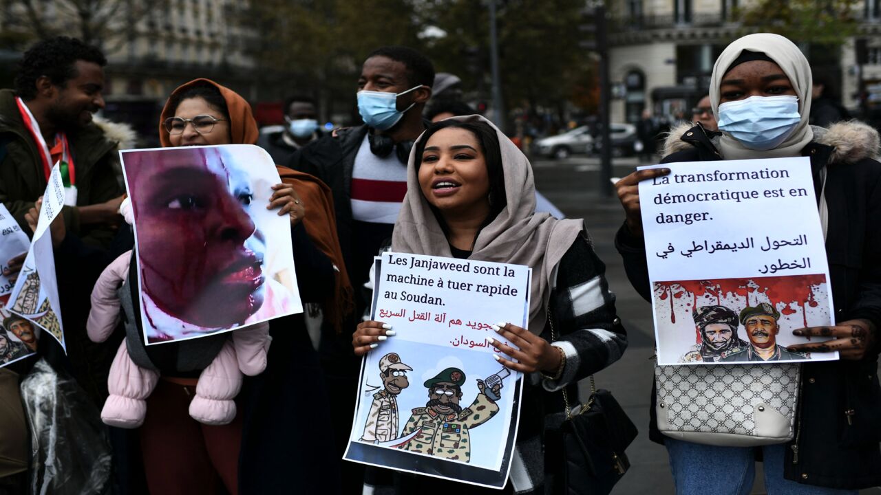 Protestors hold placards and photographs as they shout slogans during a rally to denounce the Sudanese military coup.