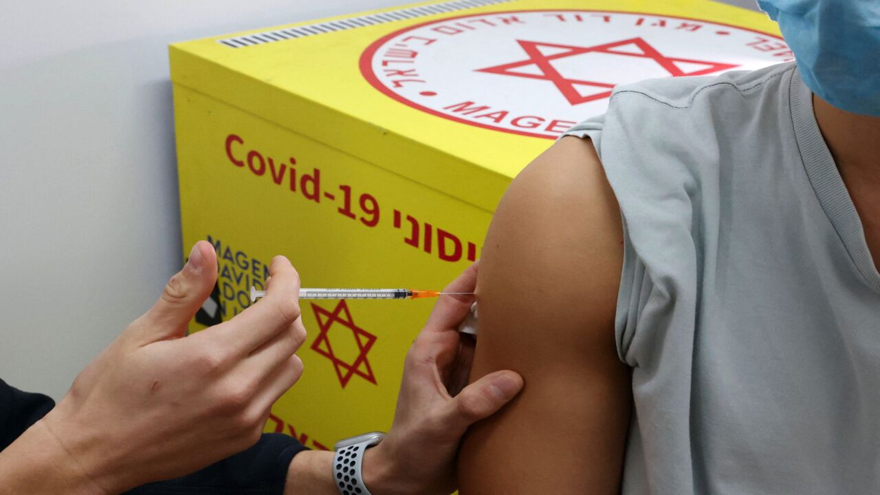 Israeli Magen David Adom administers a dose of the Pfizer-BioNTech vaccine against the coronavirus to a young man, in the Israeli town of Ramat Gan near Tel Aviv, on Dec. 23, 2021.