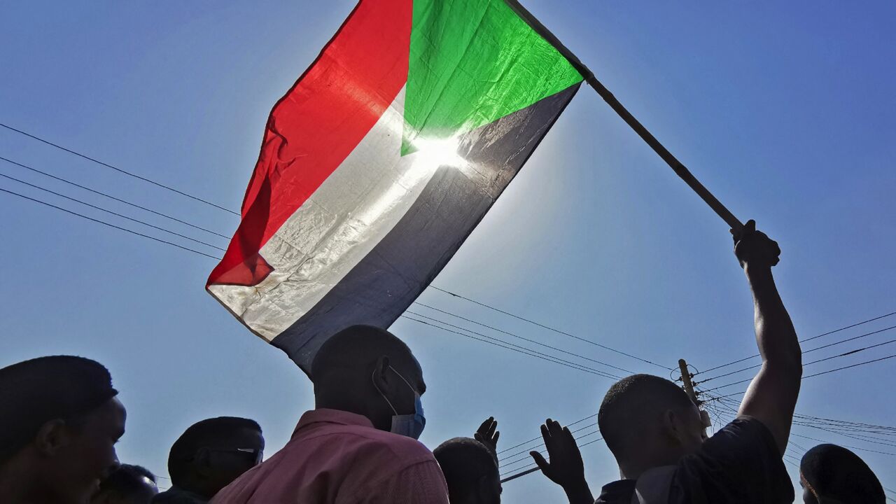 Sudanese protesters raise a national flag as they rally against the October 2021 military coup, in Khartoum on Jan. 13, 2022.