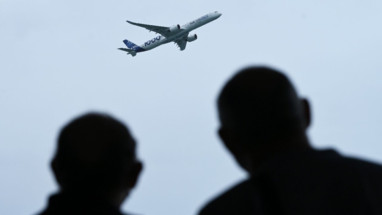 People watch as an Airbus A350 aircraft flies past at the Singapore Airshow on February 16, 2022