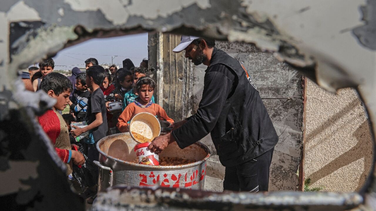 Palestinian children in the Israeli-blockaded Gaza Strip queue for free meals to break the daytime fast during the Muslim holy month of Ramadan