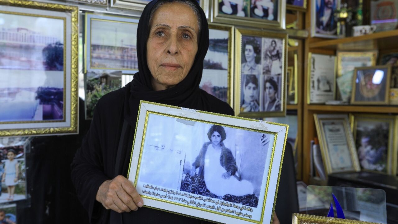 Photographer and ex-political prisoner Samira Mazaal, 77, poses with a framed picture of her on a hospital bed after being tortured