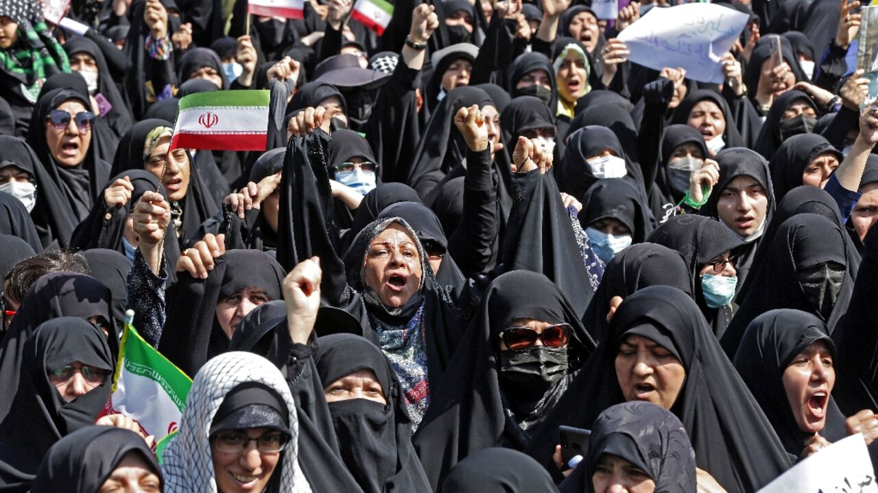 Women wearing black chador cloaks join thousands of Iranian men at a government-backed counter-demonstration in Tehran after a week of bloody protests over the country's mandatory dress code for women