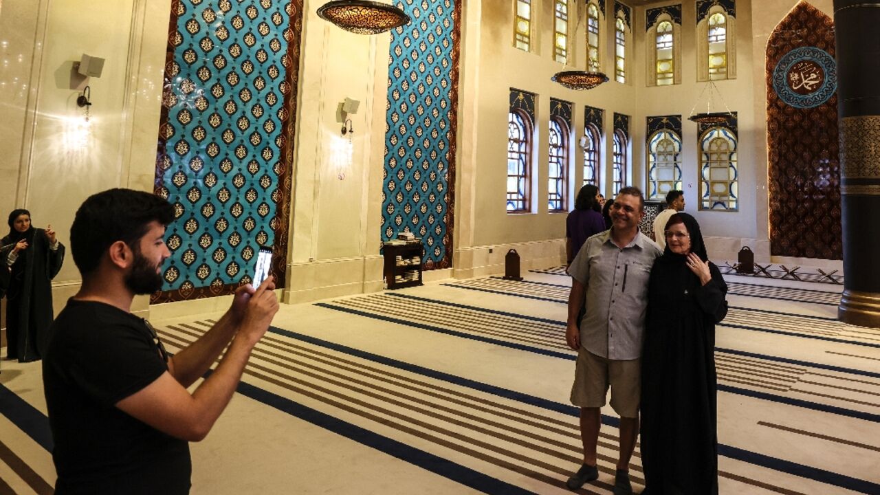 Canadian couple Dorinel and Clara Popa pose for a picture inside Doha's Blue Mosque