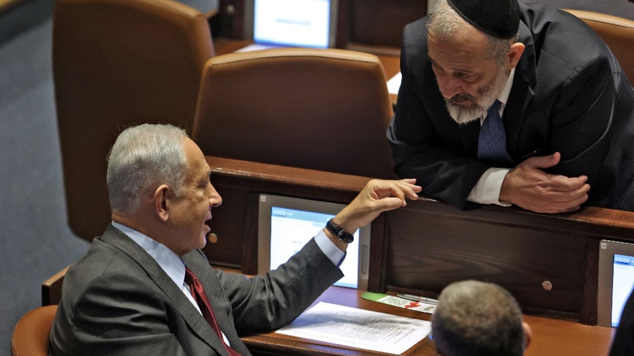 Israeli prime minister-designate Benjamin Netanyahu speaks with parliament member Aryeh Deri of the ultra orthodox  religious party Shas on December 13, 2022